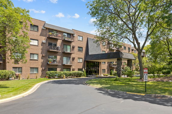 Front view of a multi-story brick apartment building with balconies.