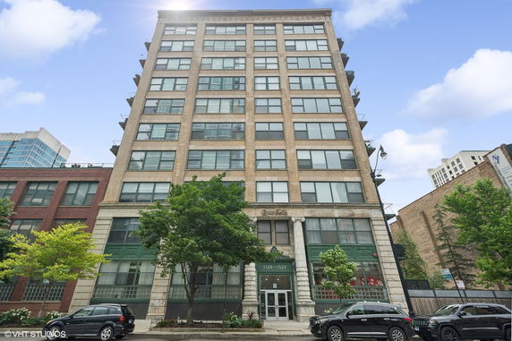 Front view of a multi-story building with large windows and columns at the entrance.