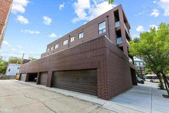 Angled view of a multi-story brick building with garages on the ground level.
