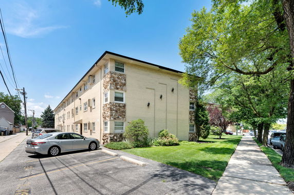 Front view of a multi-story apartment building with parking area.
