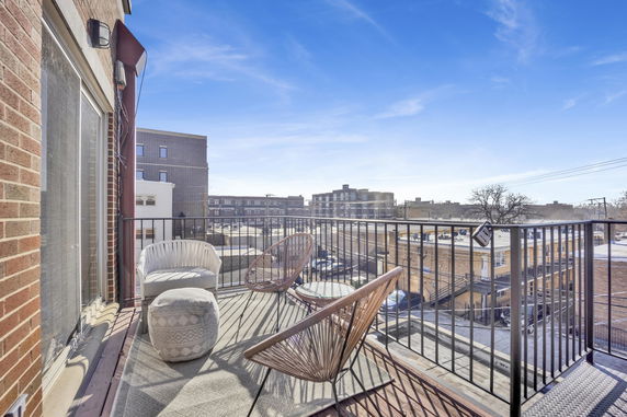 A balcony with outdoor furniture overlooking a cityscape with multiple buildings.