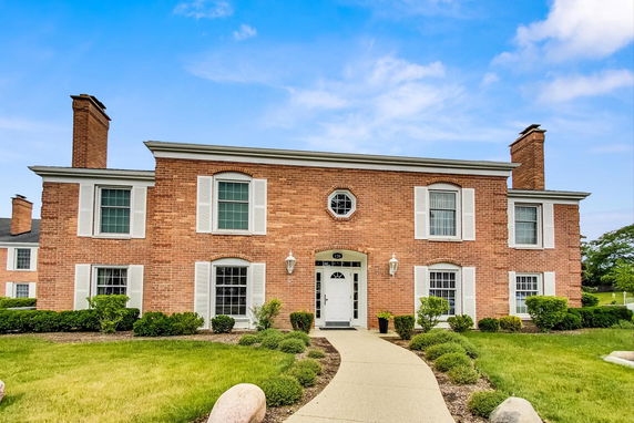 Front view of a two-story brick house with white shutters and a central entrance.