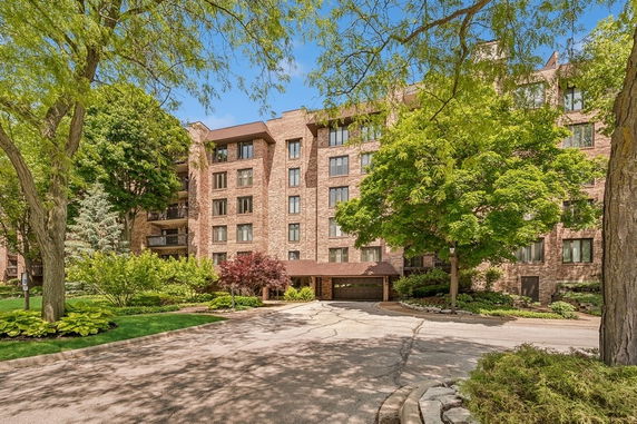 Front view of a multi-story brick apartment building with greenery.