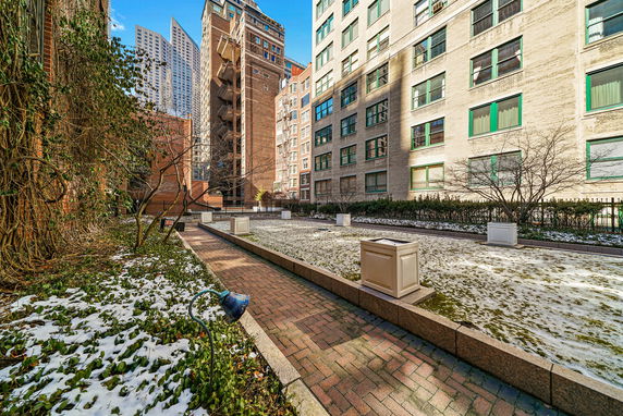 Outdoor area with buildings and a pathway surrounded by sparse vegetation and snow.