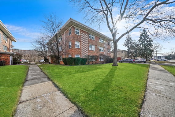 Front view of a three-story brick apartment building with a checkerboard pattern design.