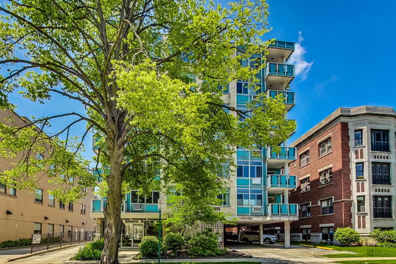 Front view of a multi-story apartment building with balconies and glass features.