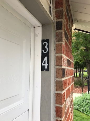 Partial view of a brick building with a door and the number 34 displayed.