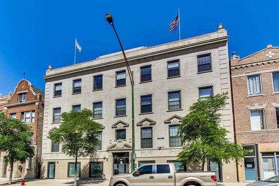 Front view of a four-story building with flags on the roof.