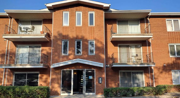 Front view of a brick apartment building with balconies.