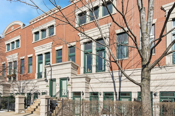 Front view of a multi-story brick townhouse with green window frames.