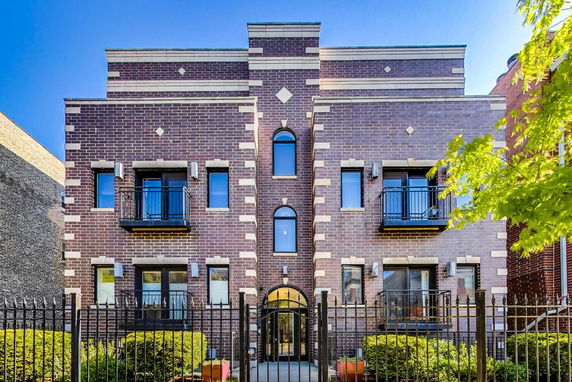 Front view of a multi-story brick building with symmetrical windows and balconies.