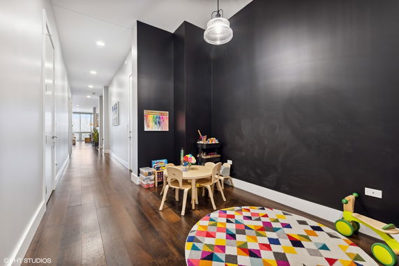 Children's play area with a small table, chairs, toys, and a colorful rug.