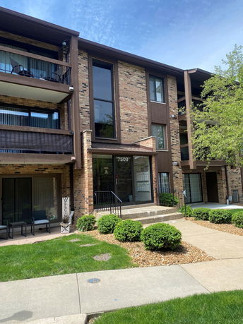 Front view of a three-story brick apartment building with balconies.