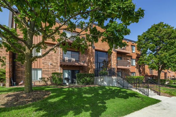 Front view of a multi-story apartment building with balconies and brick exterior.