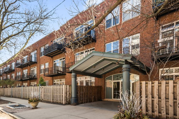 Front view of a multi-story brick building with balconies and a covered entrance.