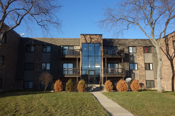 Front view of a multi-story residential building with balconies and central entrance.