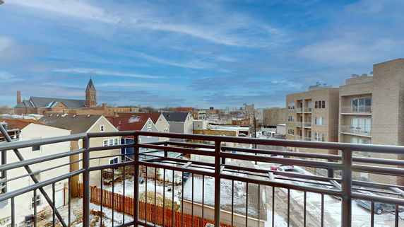 Panoramic view from a balcony overlooking residential buildings and a church.