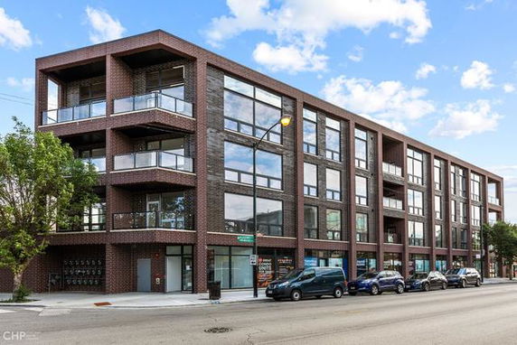 Front view of a multi-story brick apartment building with large windows and balconies.