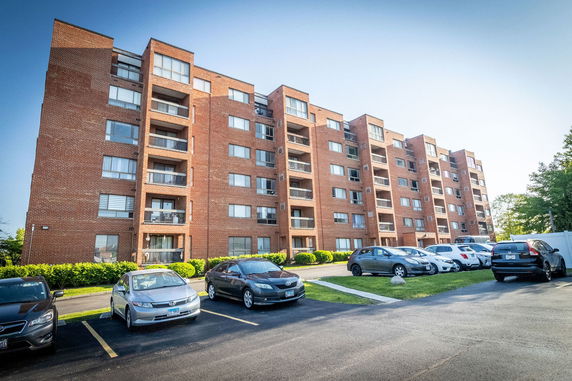 Front view of a multi-story apartment building with parked cars in front.