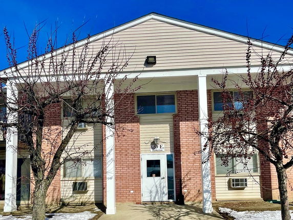 Front view of a two-story building with columns and brick facade.