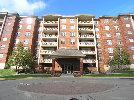 Front view of a multi-story brick apartment building with balconies and an entrance canopy.