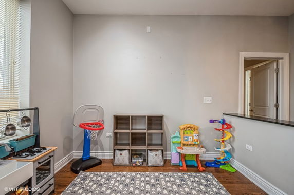 A small indoor play area with children's toys, a mini basketball hoop, and storage shelves.