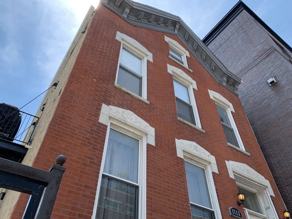 Front view of a multi-story brick building with decorative window trim.