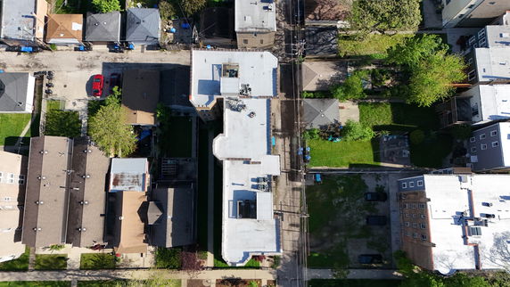 Top view of a building showcasing a flat rooftop with various equipment and neighboring buildings.