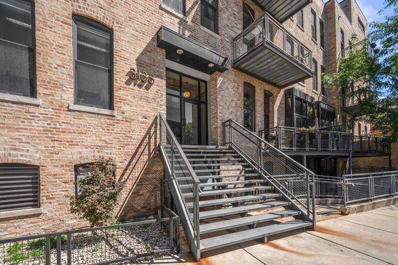 Front view of a brick building with metal stairs and balconies.