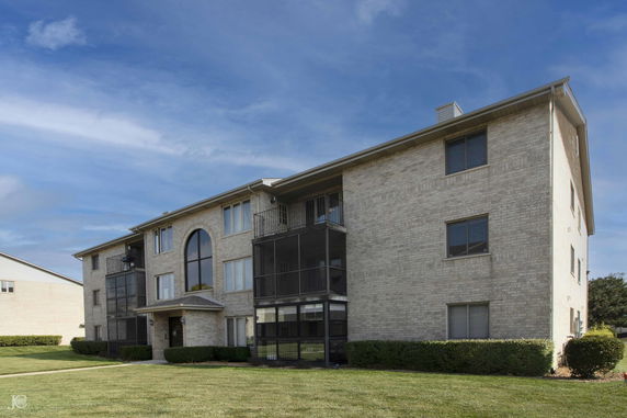 Front view of a three-story apartment building with balconies and large arched windows.