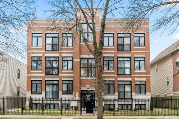 Front view of a multi-story brick apartment building with large windows.