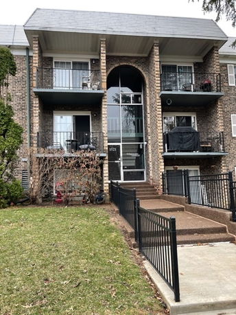 Front view of a multi-story brick apartment building with balconies.
