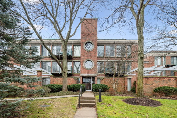 Front view of a multi-story brick building with circular windows and balconies.