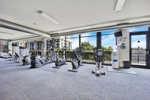Room with gym equipment and large windows.
