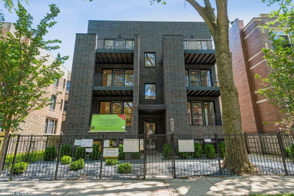 Front view of a multi-story brick residential building with balconies.