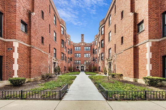 Front view of a red brick apartment building with a central entrance and symmetrical design.