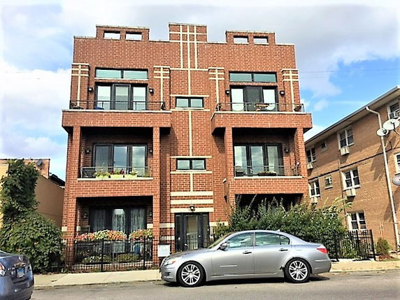 Front view of a mid-rise brick apartment building with balconies.