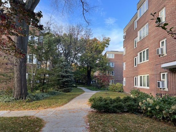Front view of a multi-story brick apartment building with multiple windows and air conditioning units.