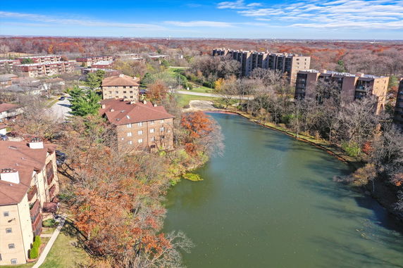 Wide view of a residential area with multiple multi-story buildings near a body of water and trees.