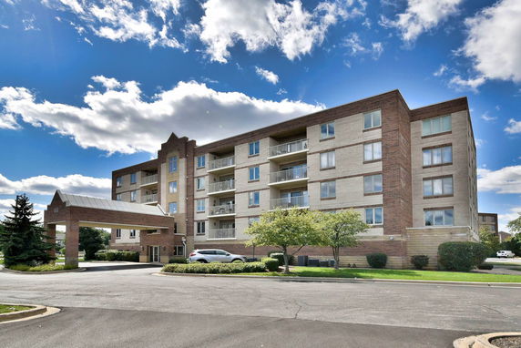 Front view of a multi-story apartment building with a parking area.