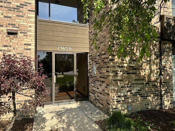 Front view of a brick building entrance with glass door.