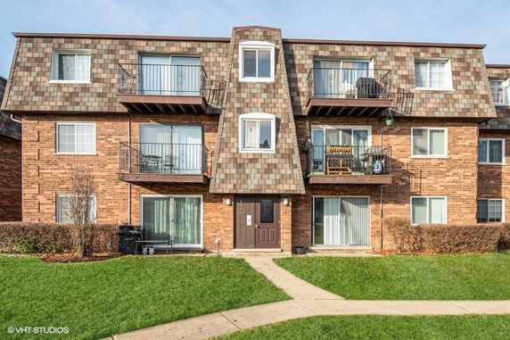 Front view of a multi-story brick apartment building with balconies.