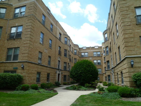Front view of a multi-story apartment building with a courtyard.