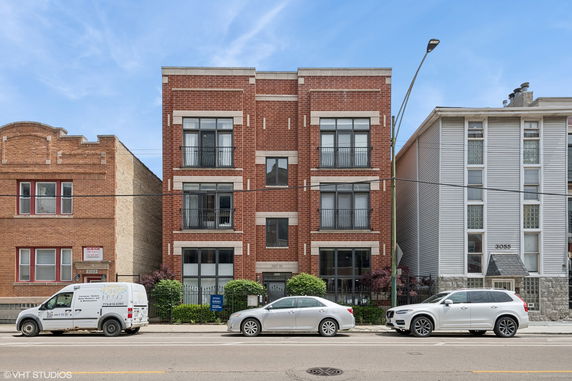 Front view of a three-story brick building with large windows.