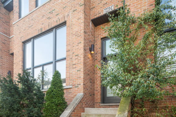 Front view of a brick house entrance with staircase and door.