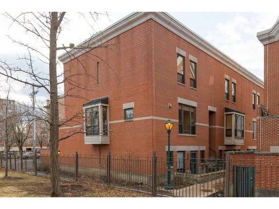 Front view of a two-story brick building with multiple windows and a fenced area.