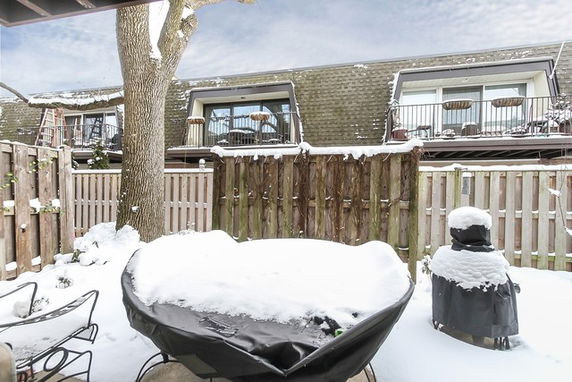 Snow-covered outdoor patio area with view of neighboring building balconies.