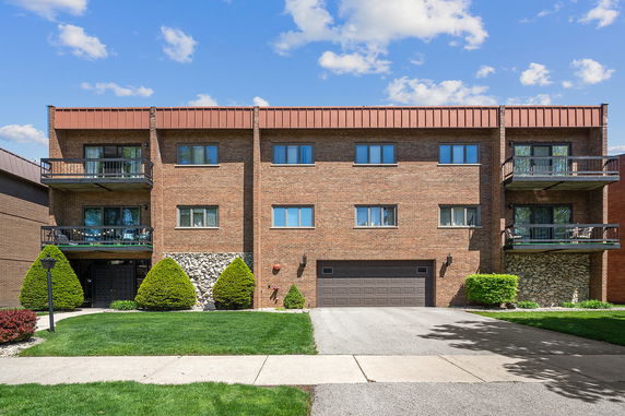 Front view of a three-story brick apartment building with balconies and a central garage.
