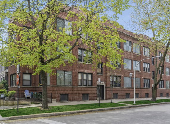 Front view of a multi-story brick building with several windows.