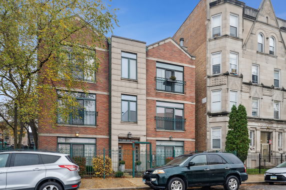 Front view of a three-story brick building with multiple windows and a gated entrance.